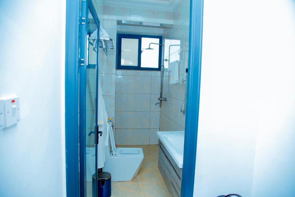 a bathroom with a shower and a toilet and a sink at BWAMI DUBAI HOTEL KASULU in Kasulu