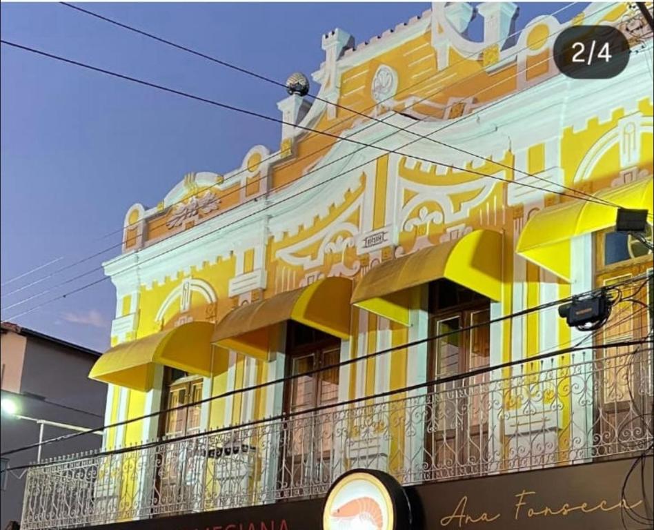 un bâtiment jaune avec un balcon devant dans l'établissement Pousada Três Arcanjos, à Cachoeira Paulista