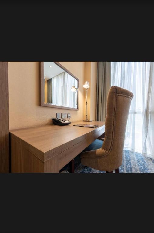 a desk with a chair and a mirror in a room at Hayat Plus Hotel in Al Madinah