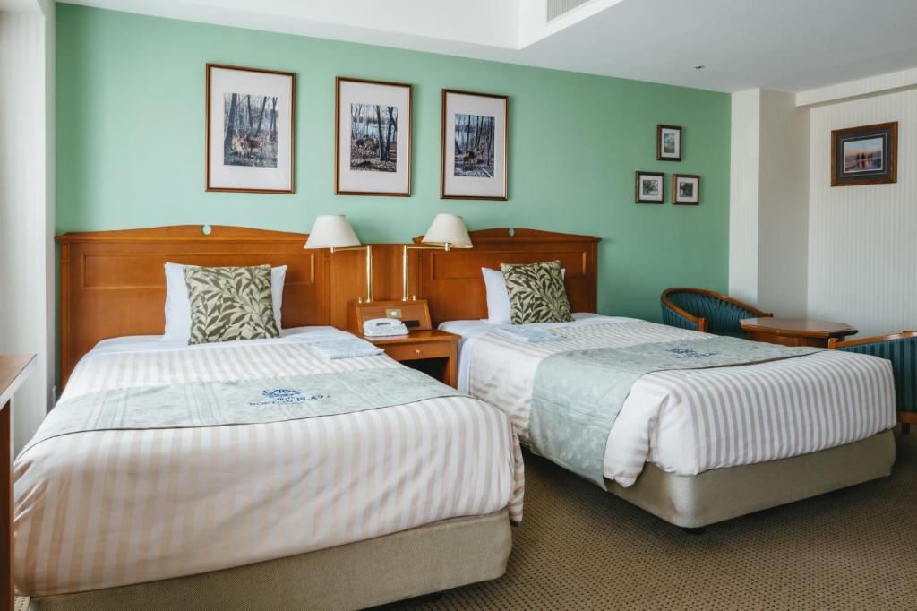 two beds in a room with green walls at Hotel Boston Plaza Kusatsu in Kusatsu