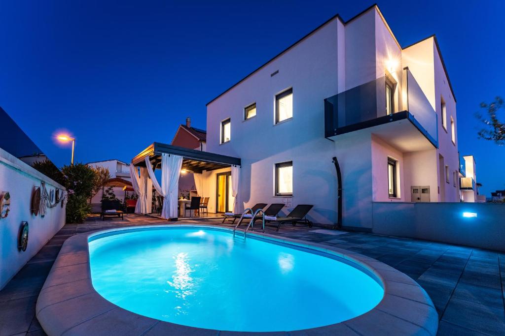a swimming pool in front of a house at night at Villa Essenza Rossa in Vodice only 650 meters from the beach in Vodice