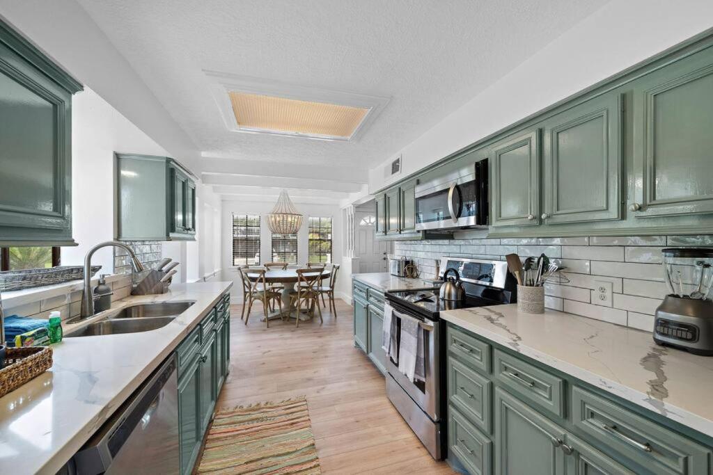 Una cocina grande con gabinetes verdes y una mesa. en Cozy home close to Kemah Boardwalk with game room, en Clear Lake Shores
