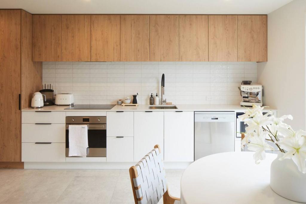 une cuisine avec des armoires blanches et une table dans l'établissement Spacious 3 Bedroom Townhouse Steps from the CBD, à Linwood