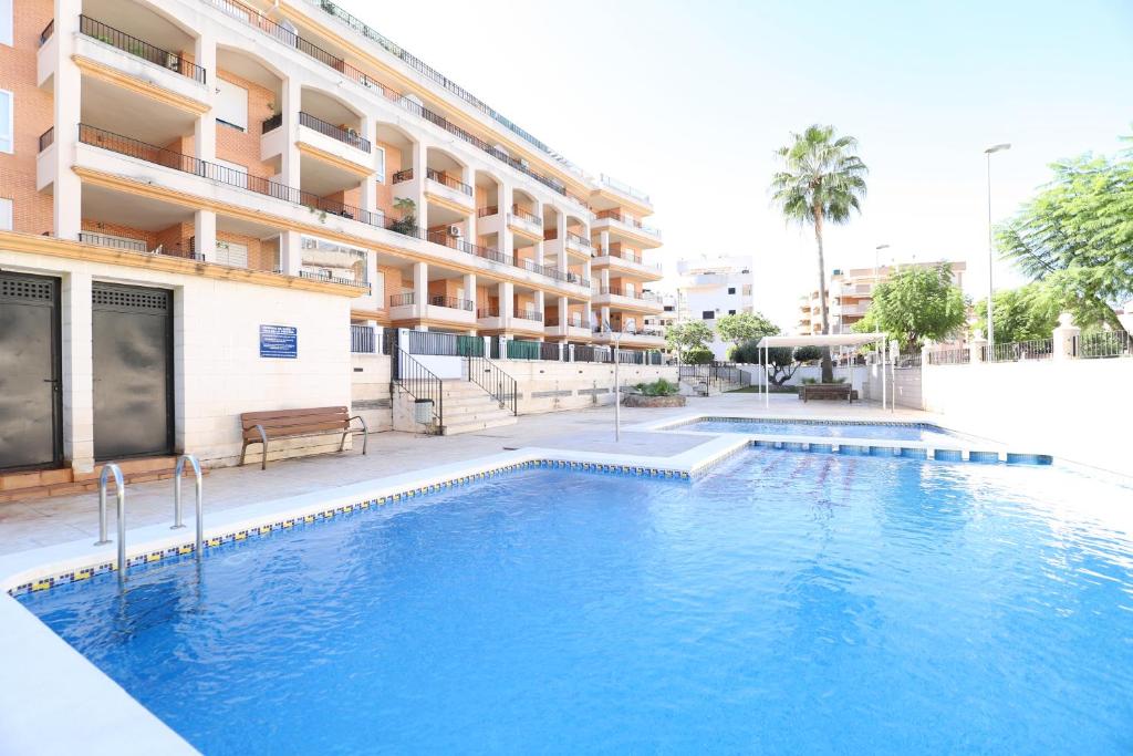 a swimming pool in front of a building at Tu refugio en Canet, piscina, parking y playa in Canet de Berenguer