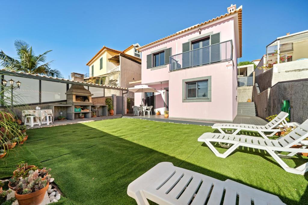 a backyard with a lawn with two white chairs at Mimi Holiday House - Free Parking in Funchal