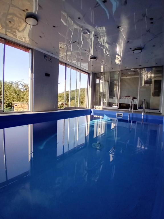 a large swimming pool with blue water and windows at Gyps Vikendica with Swimming Pool and Sauna in Tuzla