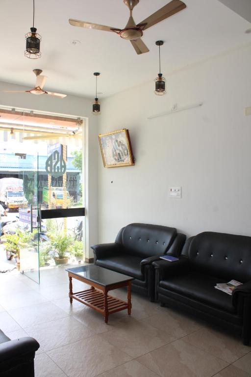 a living room with black leather couches and a coffee table at SRG Shivam Residency in Tiruvannāmalai