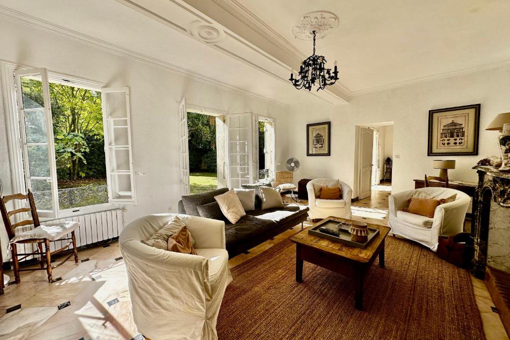 a living room with white furniture and a chandelier at La Villa de l'Horloge - Family in Montpellier! in Montpellier
