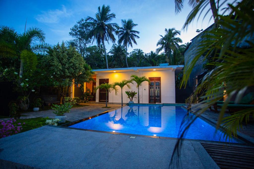 a villa with a swimming pool at night at Saku Residence in Unawatuna