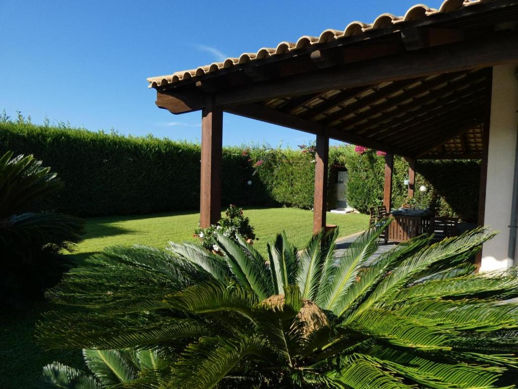 a garden with a pergola and a palm tree at Villa Baia Verde in Marina di Modica