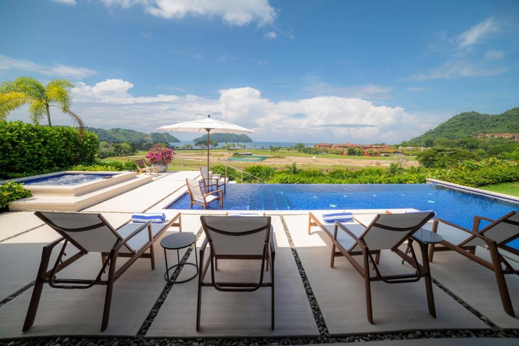 a patio with a table and chairs next to a swimming pool at Casa Ohana 5 bdrs ocean view in Los Suenos in La Mona