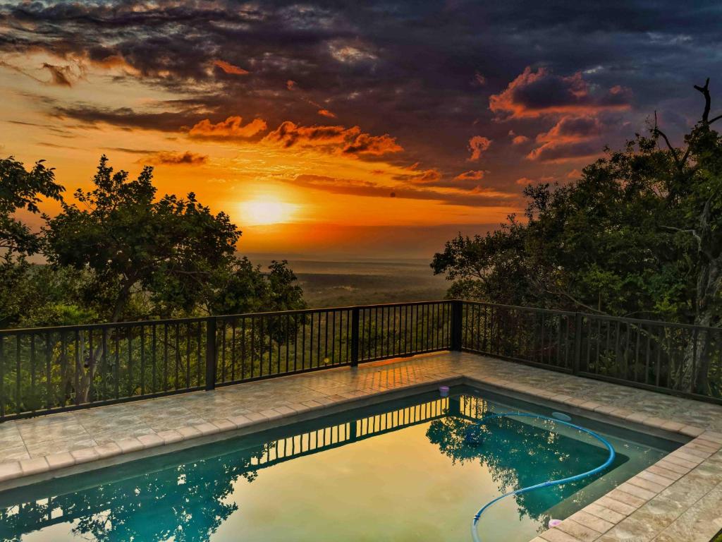 a swimming pool with a sunset in the background at vanDijksRus Farm in The Waterberg Biosphere