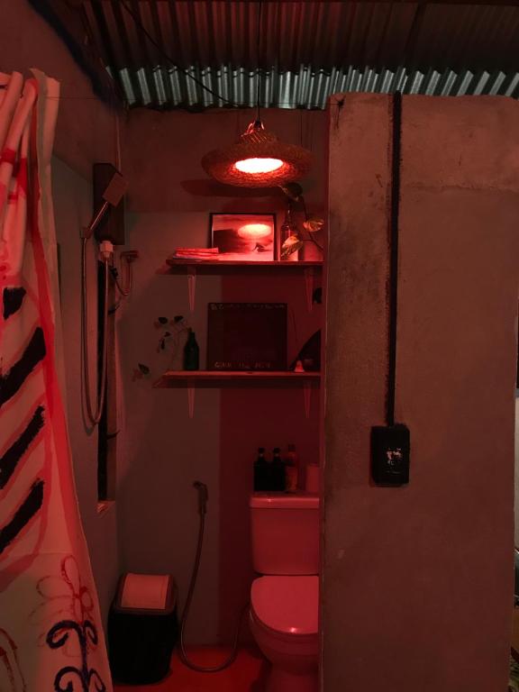 une salle de bain avec des toilettes roses et une lumière rouge dans l'établissement The Art House, à Villasis