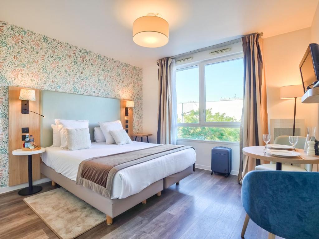 una camera da letto con un letto e una grande finestra di Séjours & Affaires Paris-Vitry a Vitry-sur-Seine