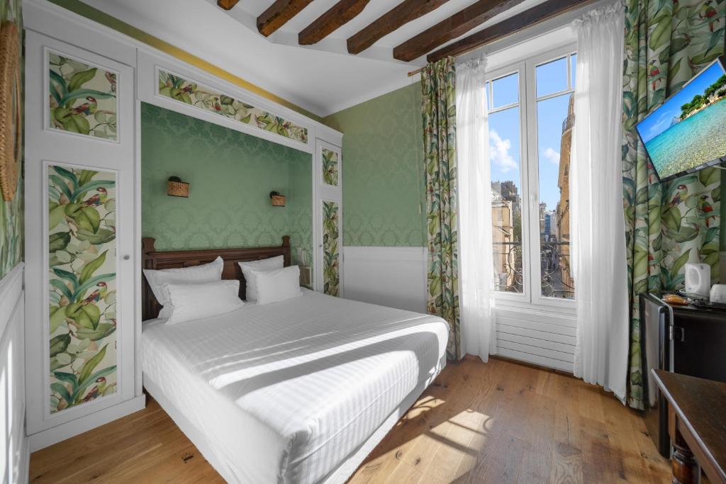 a bedroom with a white bed and a window at Hotel de la Bretonnerie in Paris