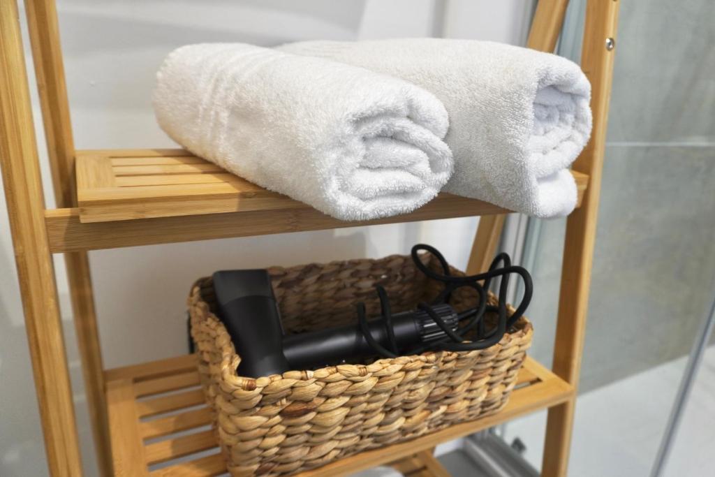 a basket with a hair dryer and towels on a shelf at OverGarden Rooms in Dossobuono