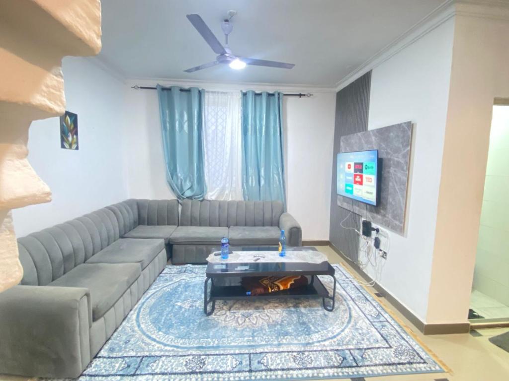 Una sala de estar con un sofá y un televisor. en Pumzika Hostings, en Mombasa