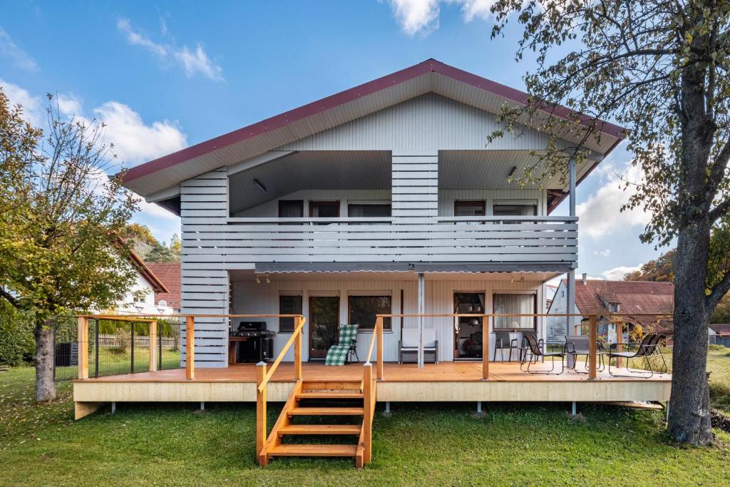 Una casa con una gran terraza con dos escaleras de madera. en Ferienwohnung an der Lauter, en Indelhausen