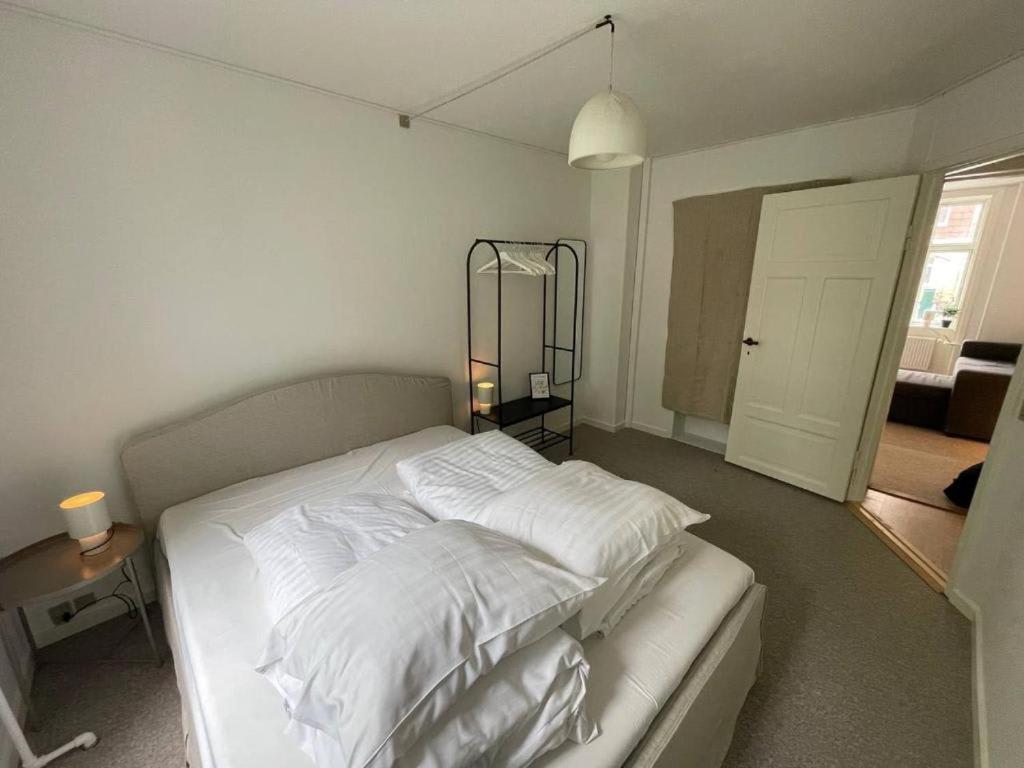 1 dormitorio con 1 cama con sábanas blancas y lámpara en Valby family apartment, en Copenhague