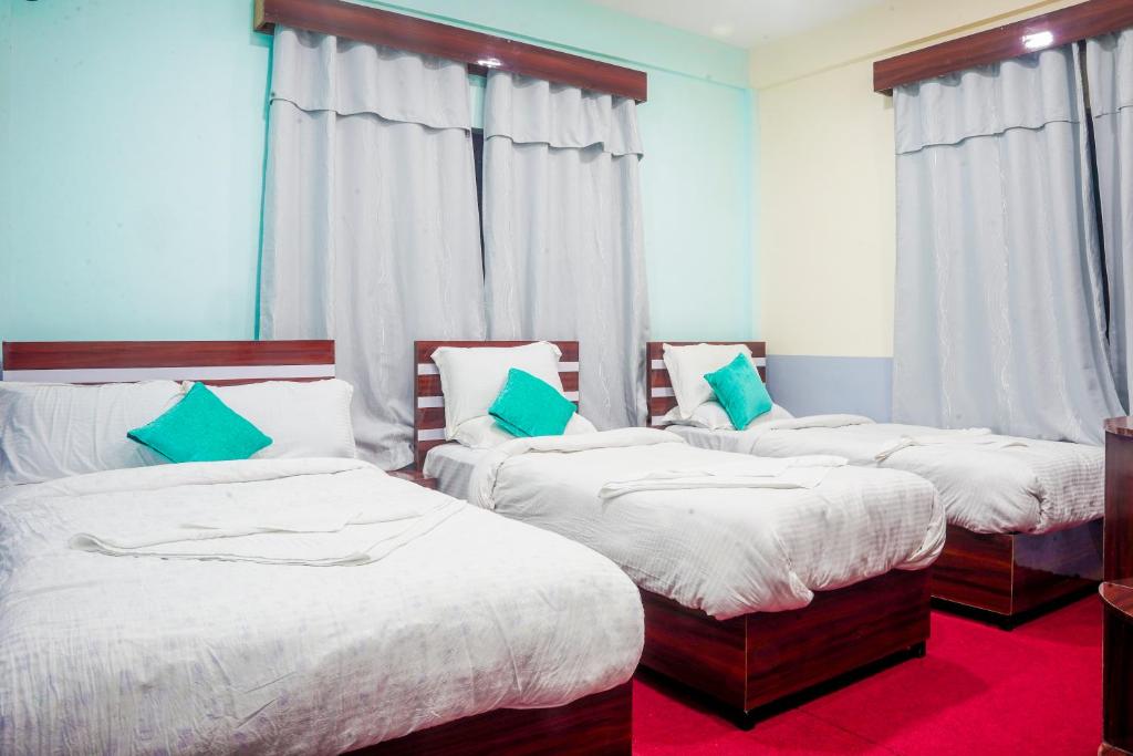 three beds in a room with blue walls and windows at Manthali Park Inn in Rāmechhāp