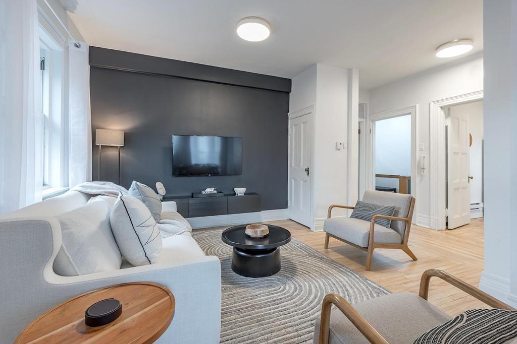 a living room with a white couch and a tv at 4BR Penthouse - Parking - 2 King & 2 Queen in Montréal