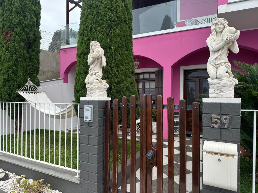 a fence with two statues in front of a pink house at Residência Mendonça in Faial