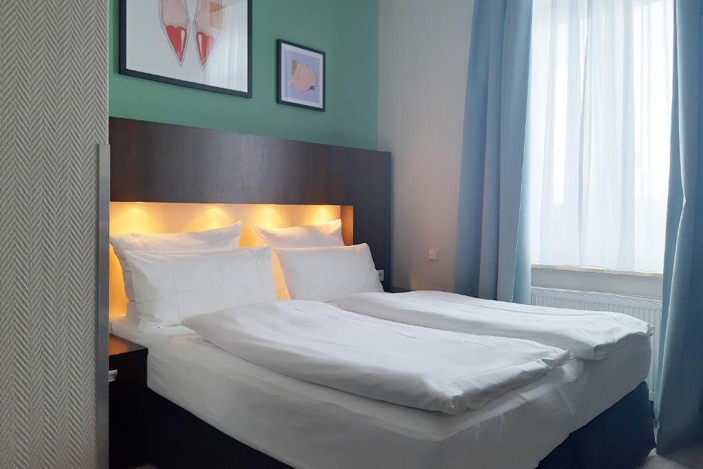 a bedroom with a large bed with white sheets and pillows at Garner Hotel Hamburg - Graf Moltke by IHG in Hamburg