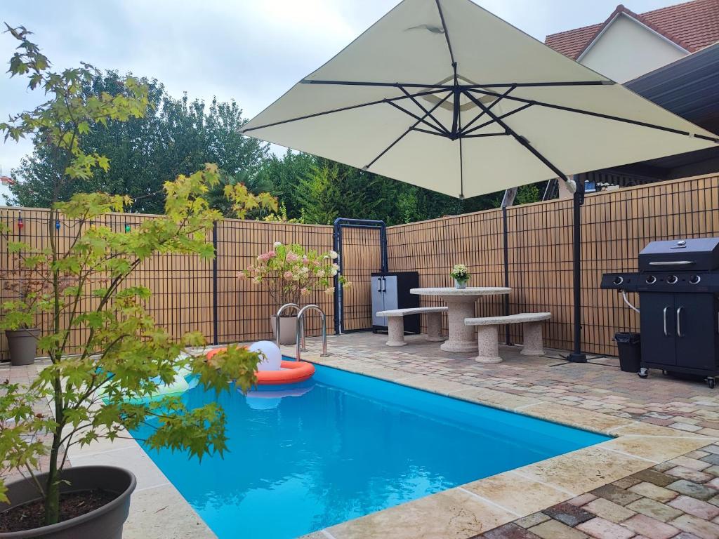 een zwembad met een parasol en een tafel en bank bij Loft envie deux in Rivery