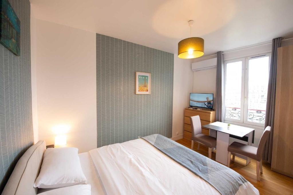 a bedroom with a bed and a table and a window at Studio number 7 in Pantin