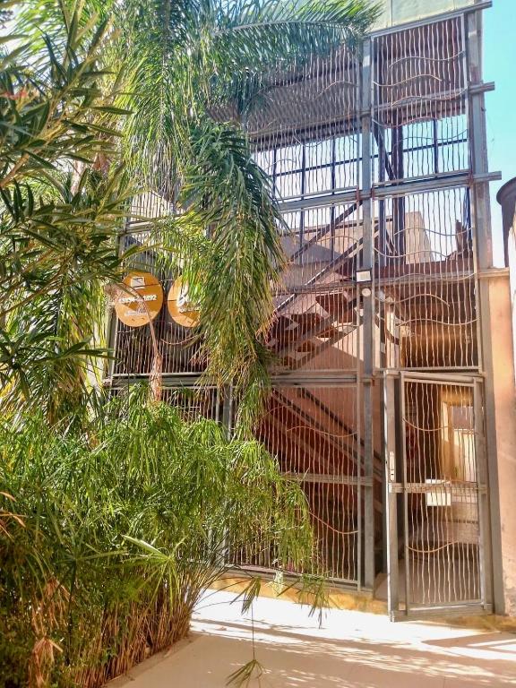 a metal gate with trees in front of a building at Apart Hotel Bell in San Fernando del Valle de Catamarca