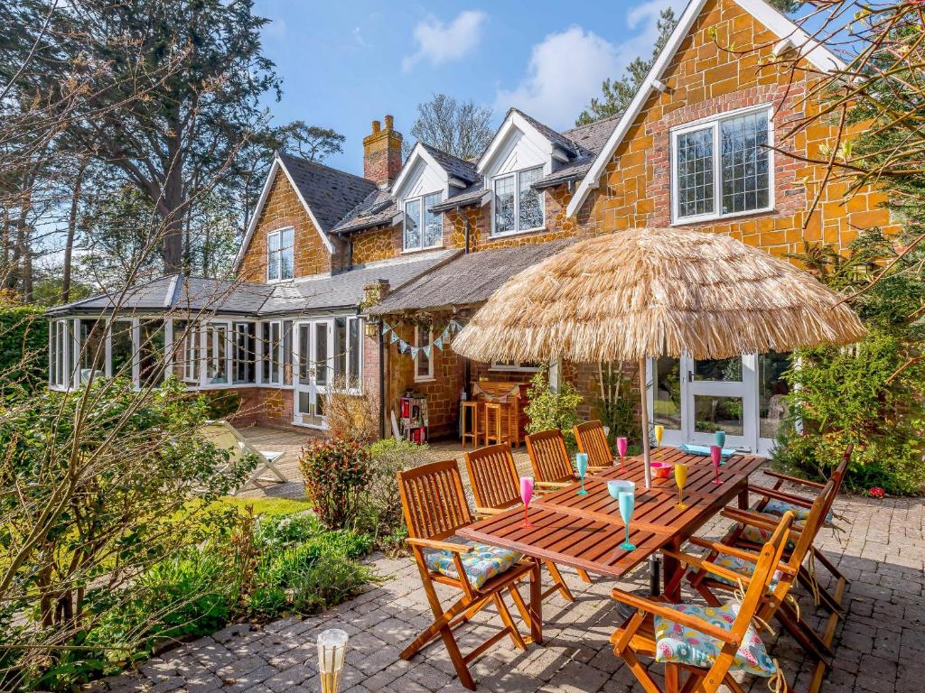 a wooden table with chairs and an umbrella in front of a house at The Old Gatehouse in Heacham