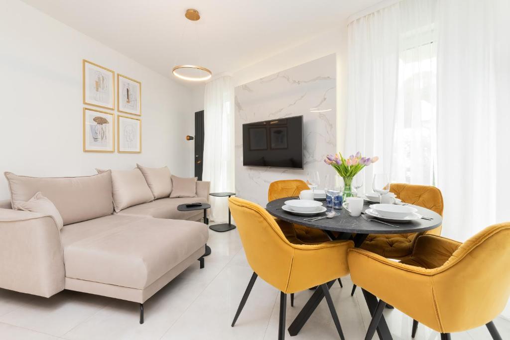 ein Wohnzimmer mit einer Couch und einem Tisch und Stühlen in der Unterkunft Piastowska 30 Garden Free Parking by Renters Prestige in Przymorze