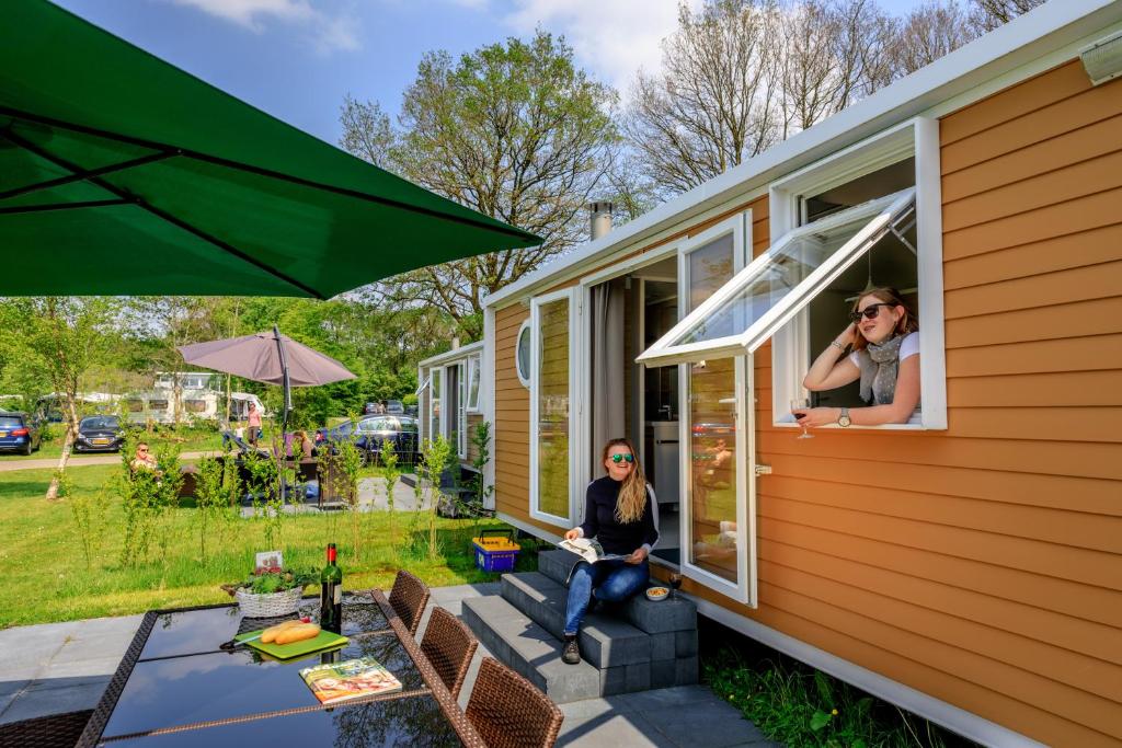 a woman sitting on the porch of a tiny house at Chalet 4 persoons in Hoogersmilde