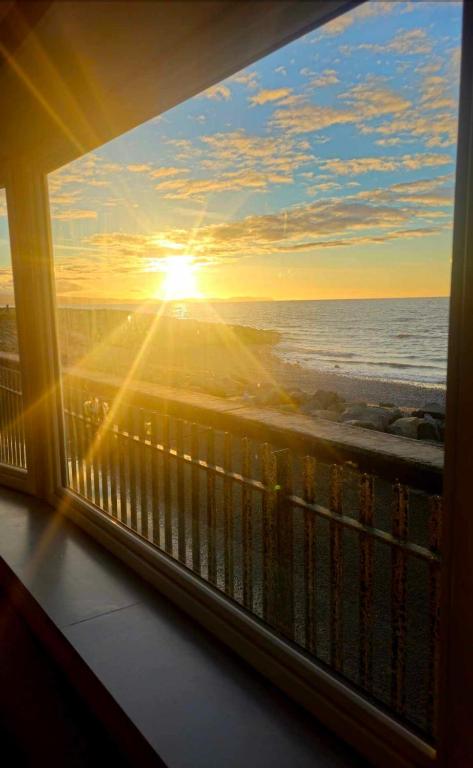 a view of the ocean from a balcony with the sunset at Sea veiw in Kinmel Bay