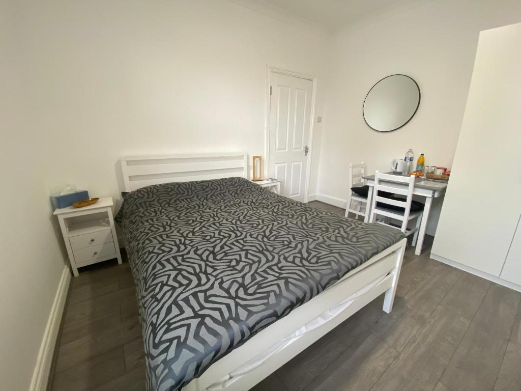 a bedroom with a bed and a table and a mirror at Watford Junction Stay in Watford
