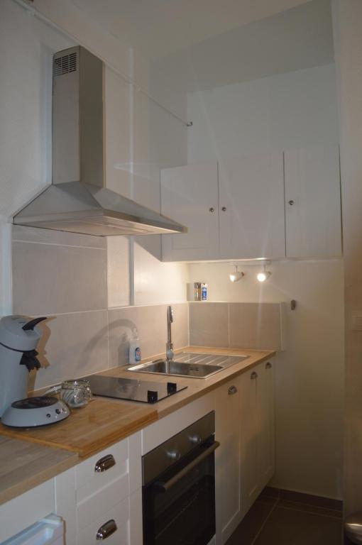 Una cocina con gabinetes blancos y un fregadero. en Maison Nova, en Talant