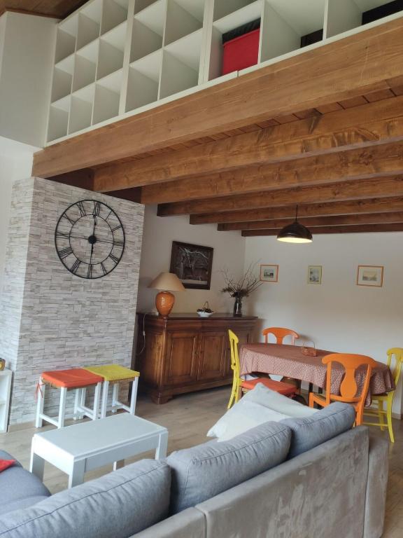 a living room with a couch and a clock on the wall at Duplex with spectacular mountain views for 8 in Porté-Puymorens