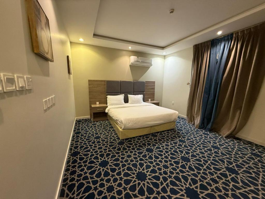 a bedroom with a bed with a blue and white carpet at ليالي رهيف للشقق المخدومه in Abha