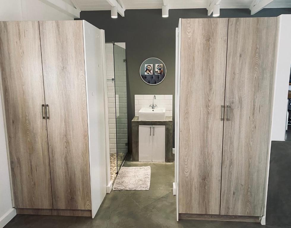 een badkamer met twee houten deuren en een wastafel bij Blouberg Rise Cottage in Kaapstad