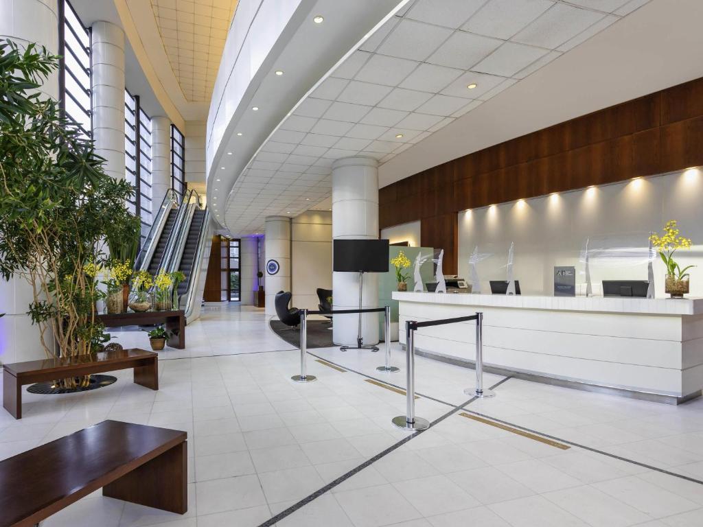 an office lobby with a reception desk and tables at Mercure Sao Paulo Grand Plaza Paulista in Sao Paulo