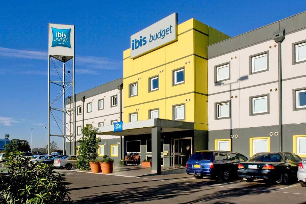 a yellow building with cars parked in a parking lot at ibis Budget - Melbourne Airport in Melbourne