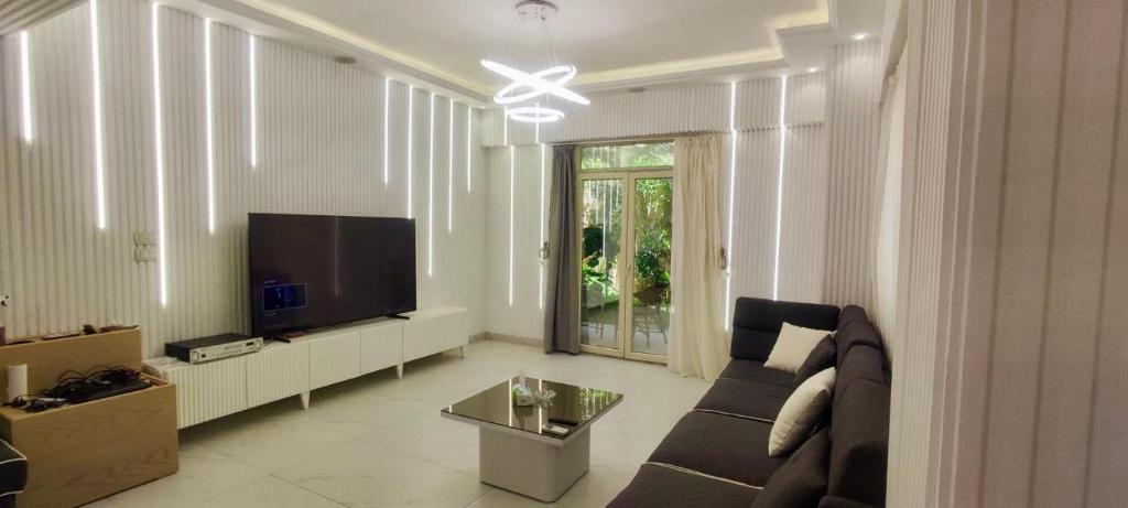 a living room with a couch and a flat screen tv at دوبلكس مفروش فندقي in Madīnat ash Shurūq