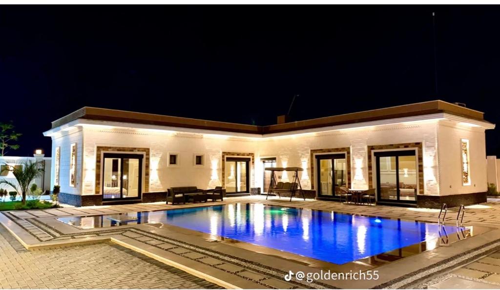 a large swimming pool in front of a house at night at Reef Golden Resort شاليه الريف الذهبي in Qaryat ash Shamālī