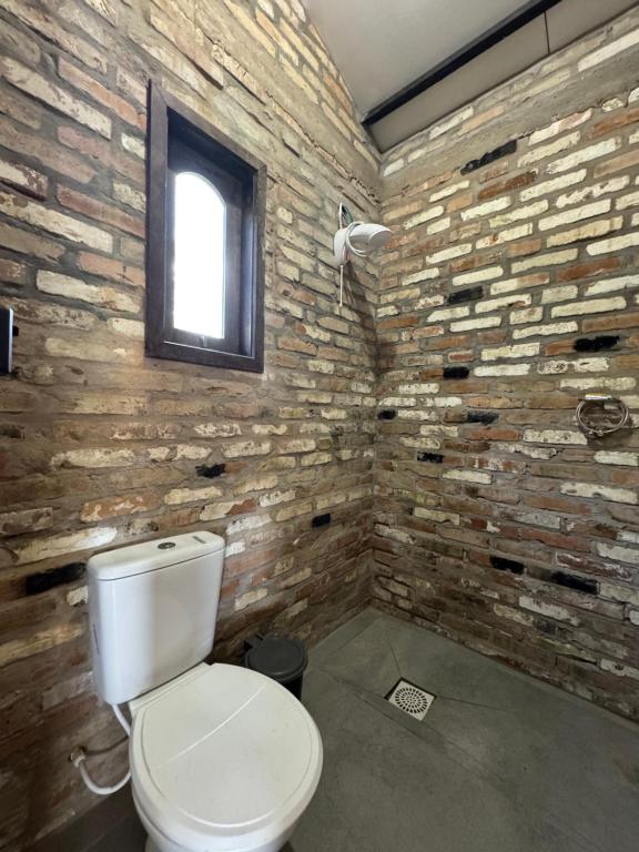 ein Badezimmer mit Toilette und einer Ziegelwand in der Unterkunft Pico da neblina in Farroupilha
