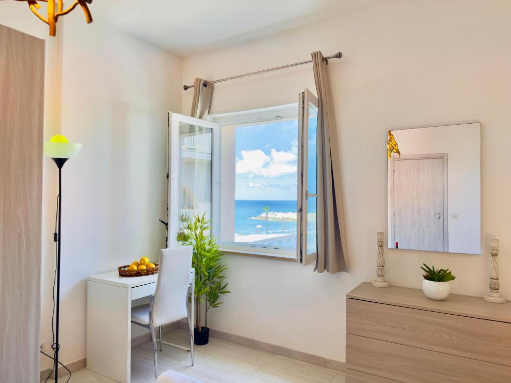 カステル・ヴォルトゥルノにあるDemetra Seafront Apartment - Parking & Poolのデスク、海の景色を望む窓が備わる客室です。