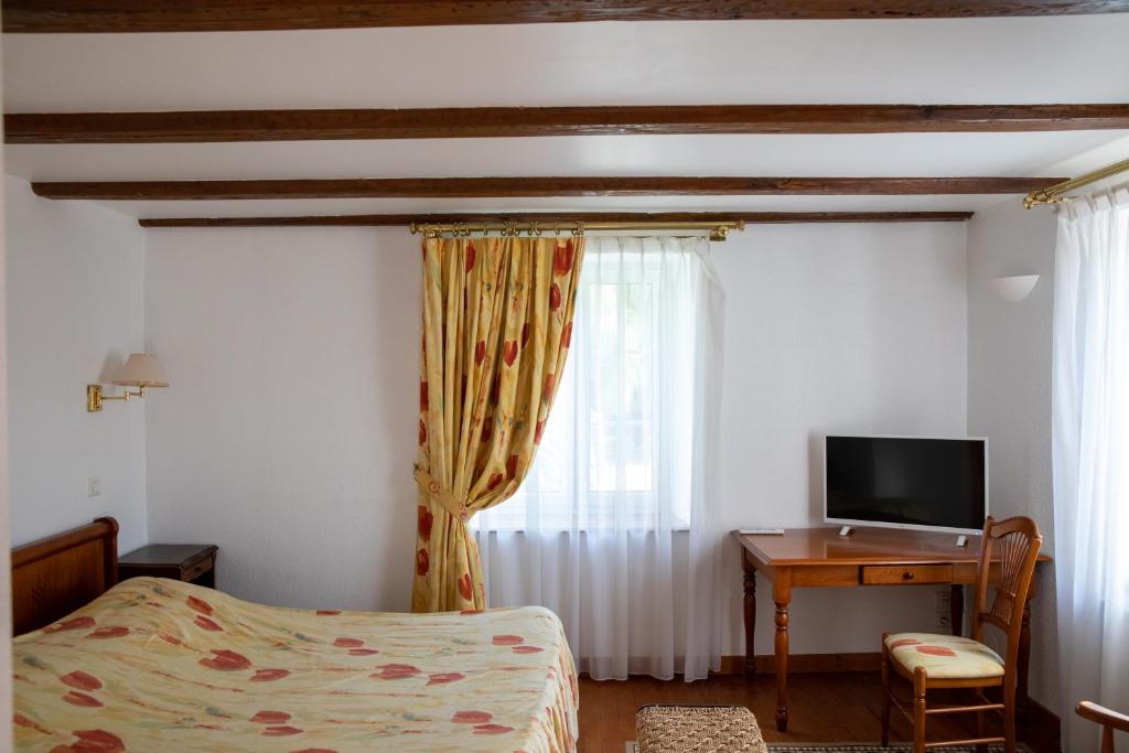 a bedroom with a bed and a desk with a television at La ferme du Franz in Diefmatten