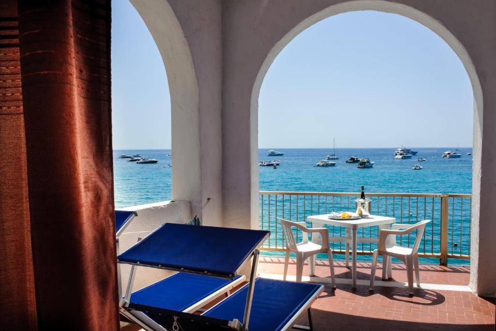 a balcony with a table and chairs and the ocean at Hotel Regina del Mare in Ischia