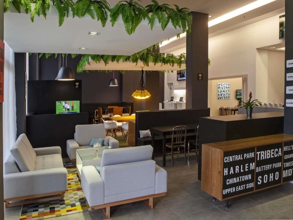 a lobby with chairs and a table and a restaurant at ibis Styles Maracanau in Maracanaú