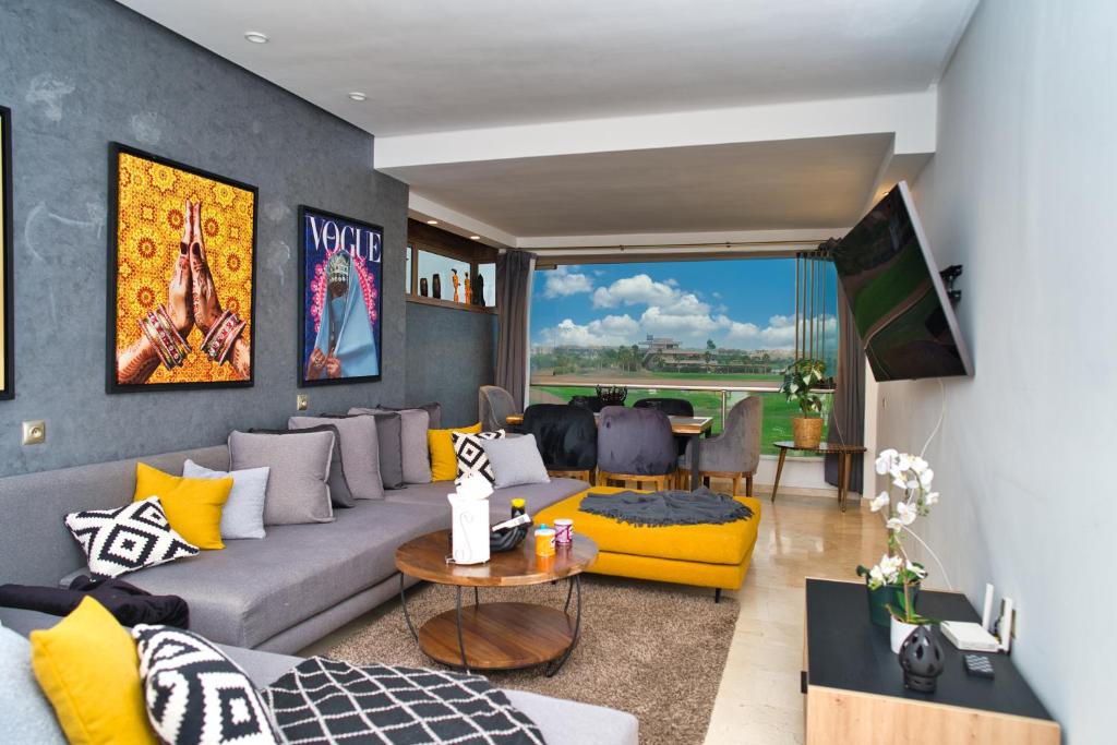 sala de estar con sofá gris y detalles amarillos en Prestigia, superbe appartement, vue sur golf, piscine et Atlas, en Marrakech