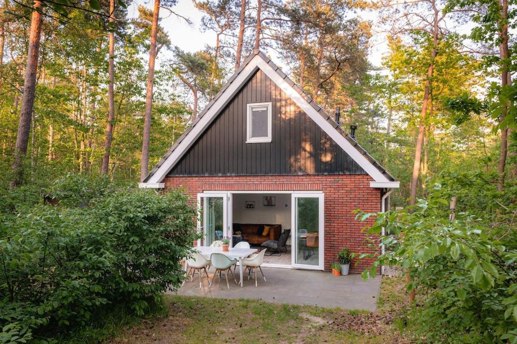 Cette petite maison dispose d'une terrasse dans les bois. dans l'établissement Grove Den I Heerlijk vakantiehuis met bosrijke tuin, à Nunspeet